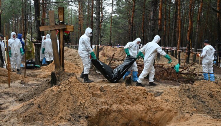 Investigadores se llevan una bolsa de cadáveres en Izium, Ucrania