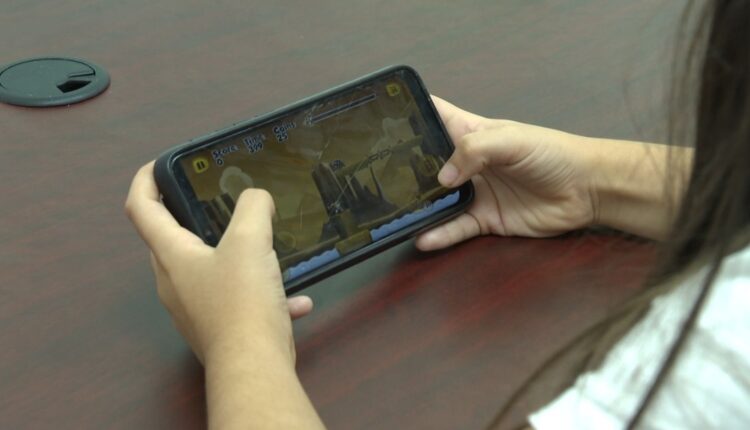 Niña jugando videojuegos en teléfono celular