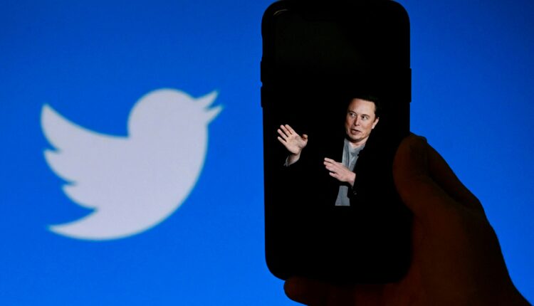 Persona sosteniendo celular mostrando fotografía de Elon Musk y de fondo la imagen de Twitter