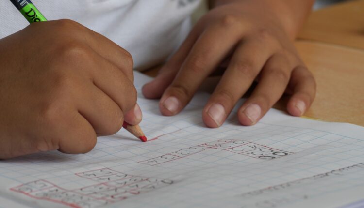 Estudiante escuela primaria escribiendo sobre cuaderno en clases.