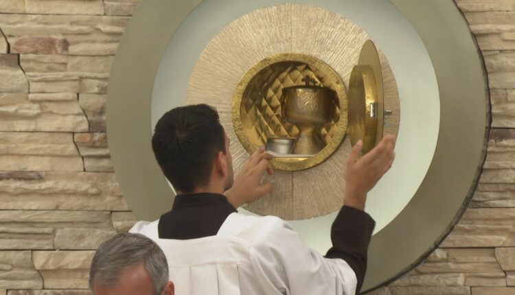 Acólito sacando los ornamentos sacerdotales para la comulgación de los feligreses en evento religioso.