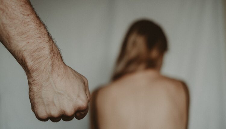 Hombre parado detras de una mujer que tiene la espalda descubierta.