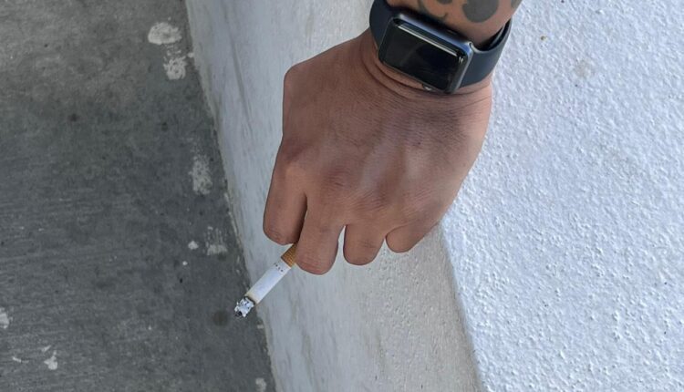 Hombre sostiene un cigarro encendido.