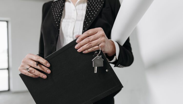 Mujer trabajadora de bienes raíces sosteniendo un portafolio y llaves de una casa