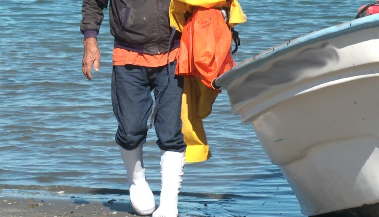 Pescador saliendo de una embarcación a la orilla de la playa.