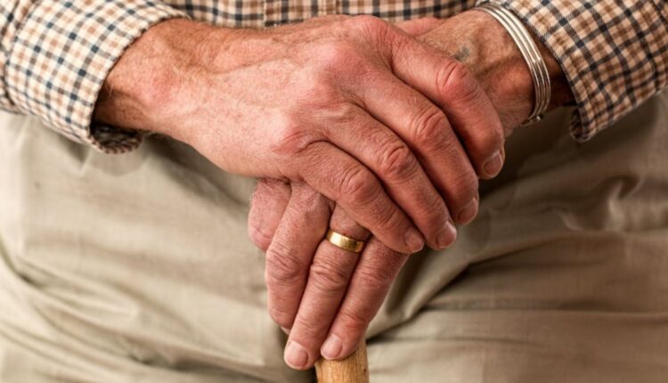 Unas manos de una persona de la tercera edad sosteniendo un bastón