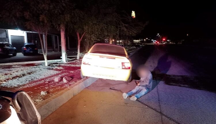 joven tirado junto a su vehículo chocado