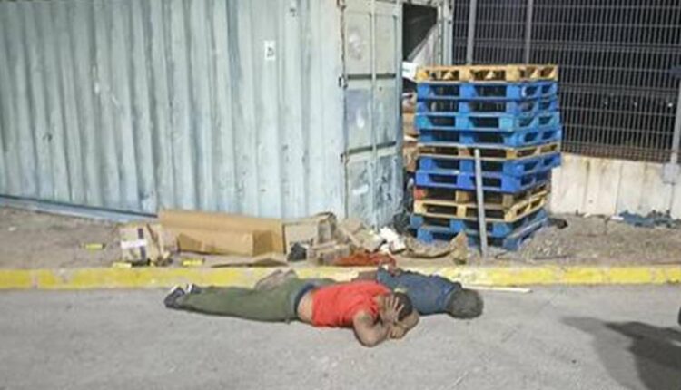 Dos hombres acostados bajo pecho junto a un contenedor