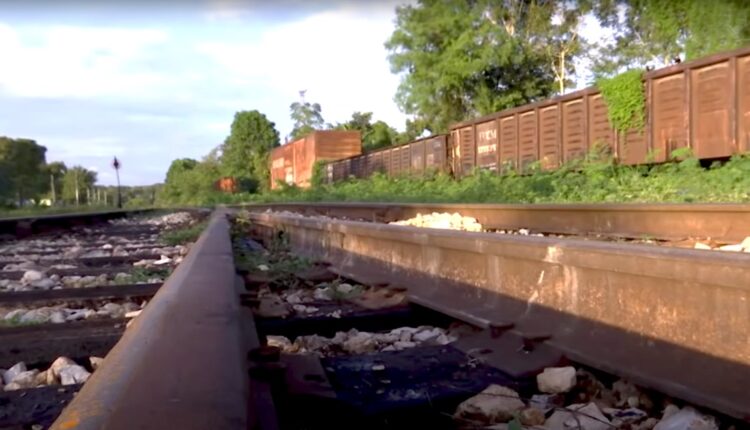 vías de tren y vagones oxidados al fondo